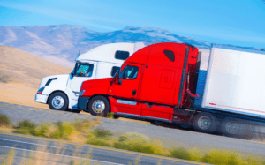Two white and red trucks on an expressway