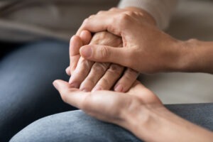 A wrongful death lawyer in Maumee consoling a client who lost a loved one with a touch on the hand.