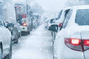 Many cars lined up in traffic in the middle of a snowstorm on a road